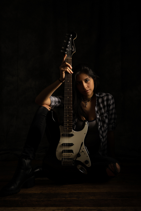 Talented young woman confidently holding an electric guitar, ready to rock the stage.