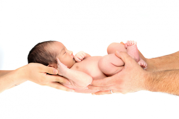 Loving parental hands cradling their precious newborn with care and tenderness.