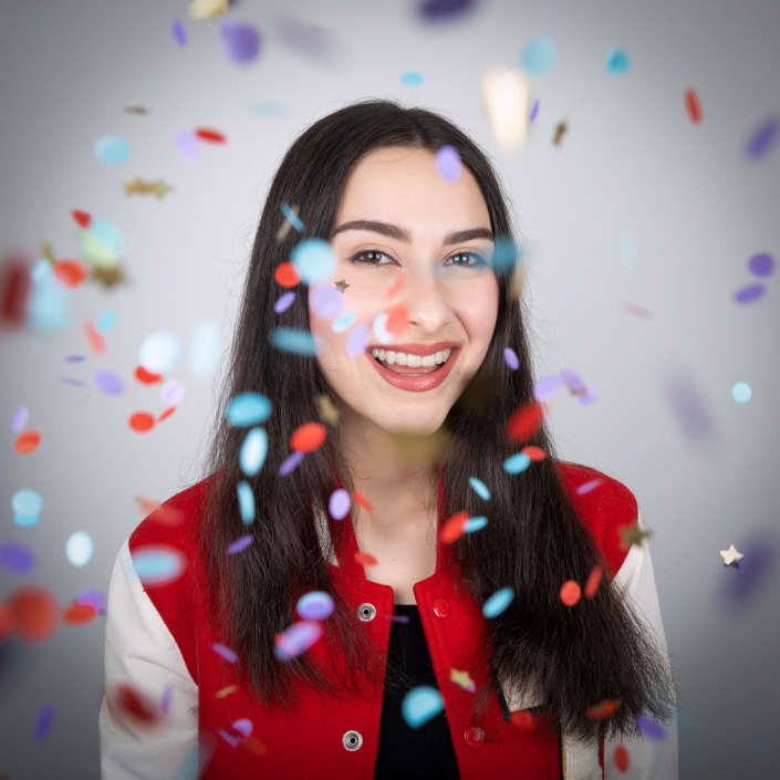 Dynamic image of a girl wearing a lively university red and white jacket, radiating a spirited and celebratory atmosphere.