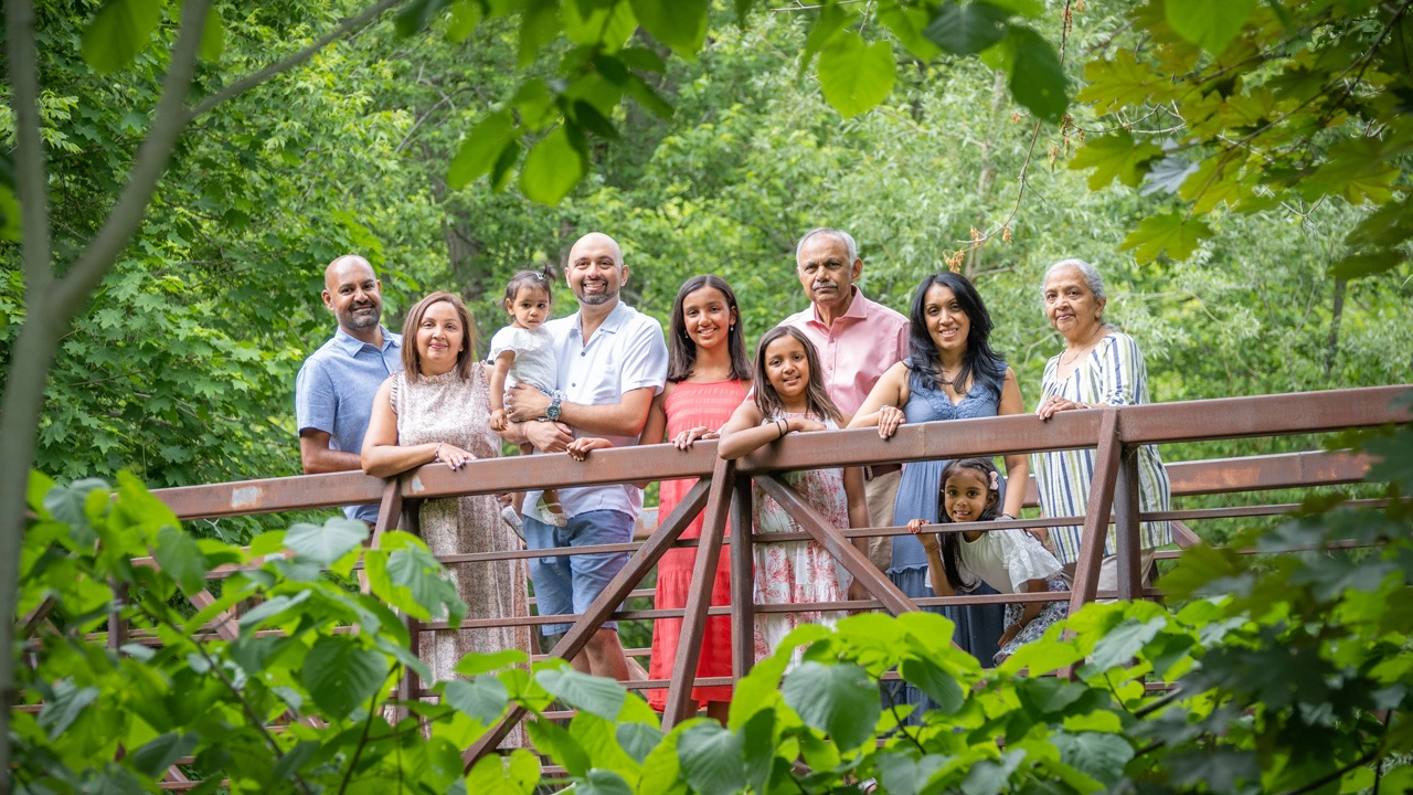Large Indian family at Lowville Park, positioned on a bridge and beautifully framed by tree leaves.