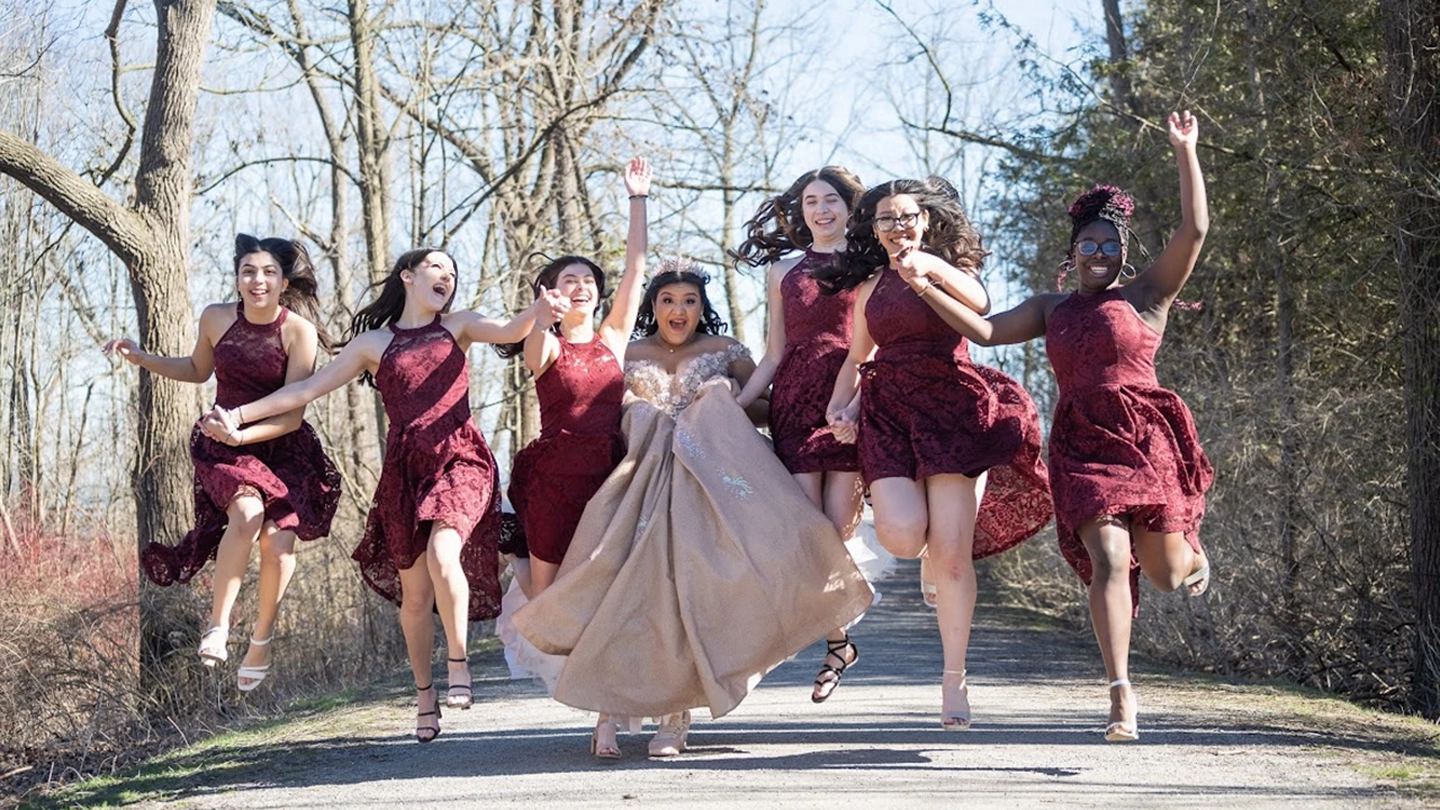 Seven teenage girls leap into the air, their faces glowing with joy, as they celebrate the sweet 16 milestone of one of their own.